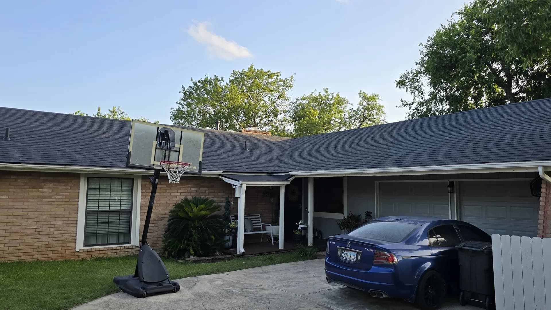 Single-story brick ranch home with a completed new dark gray architectural shingle roof, front view with driveway.