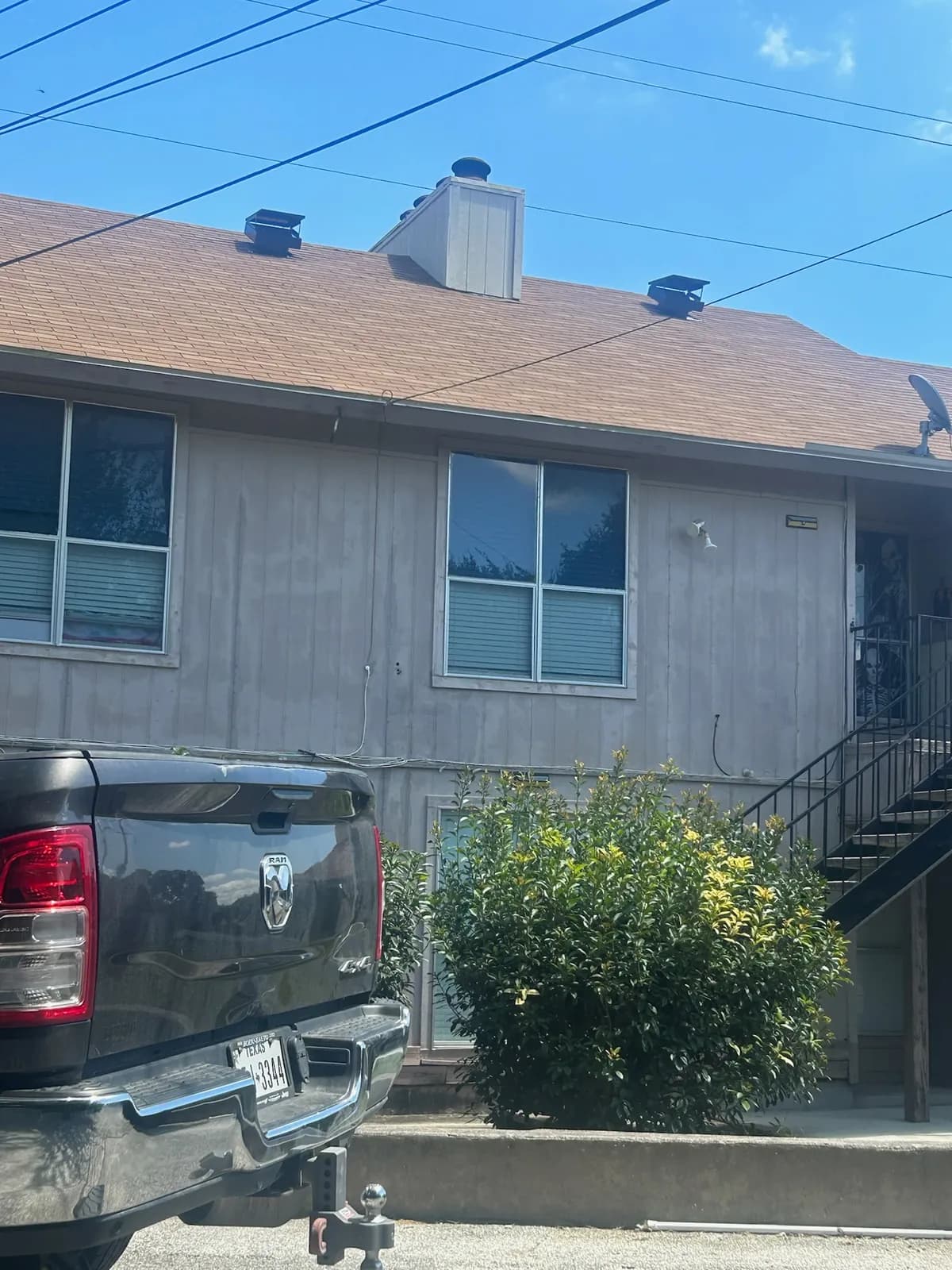 Two-story stucco home with a completed tan shingle roof and new chimney cap, pickup truck parked below.